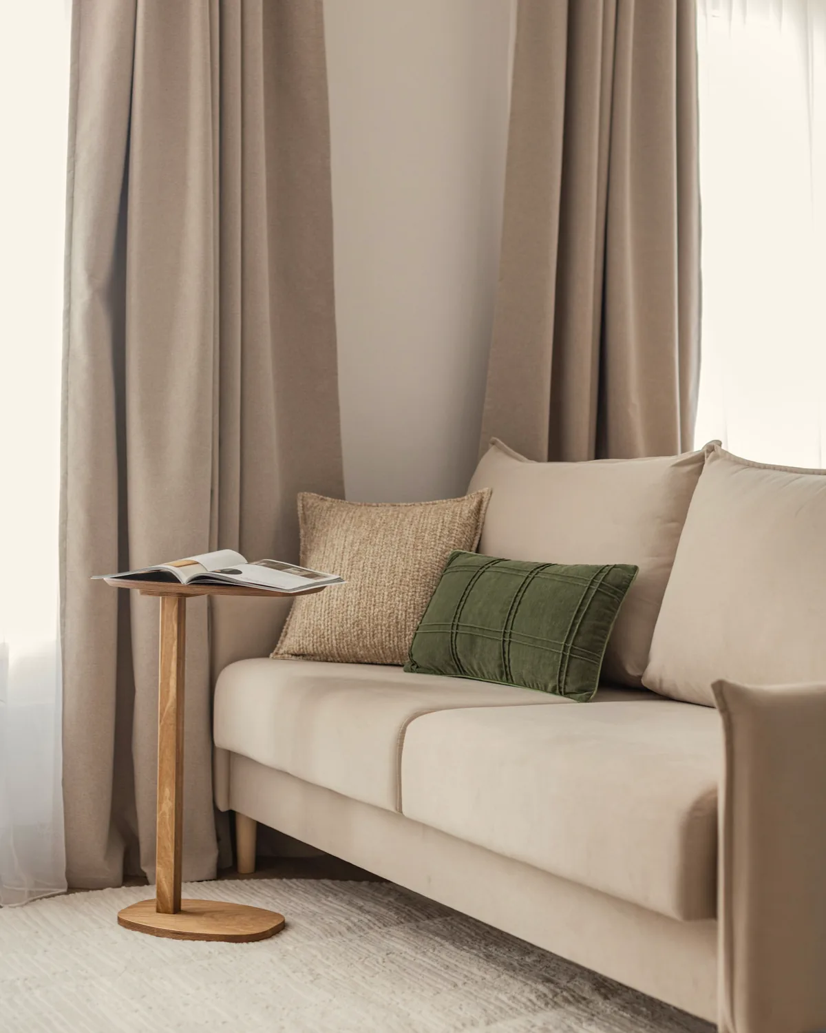 A beige sofa with cushions and a side table, placed in a room