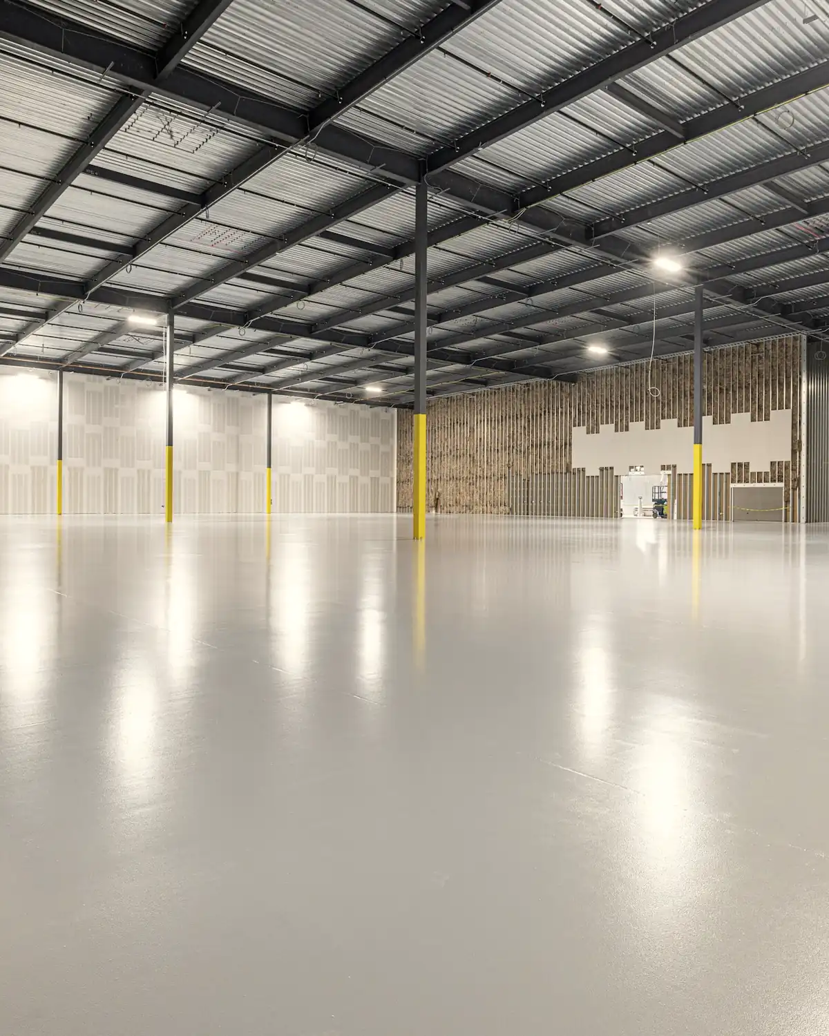 An empty, brightly lit warehouse with a pale polished concrete floor