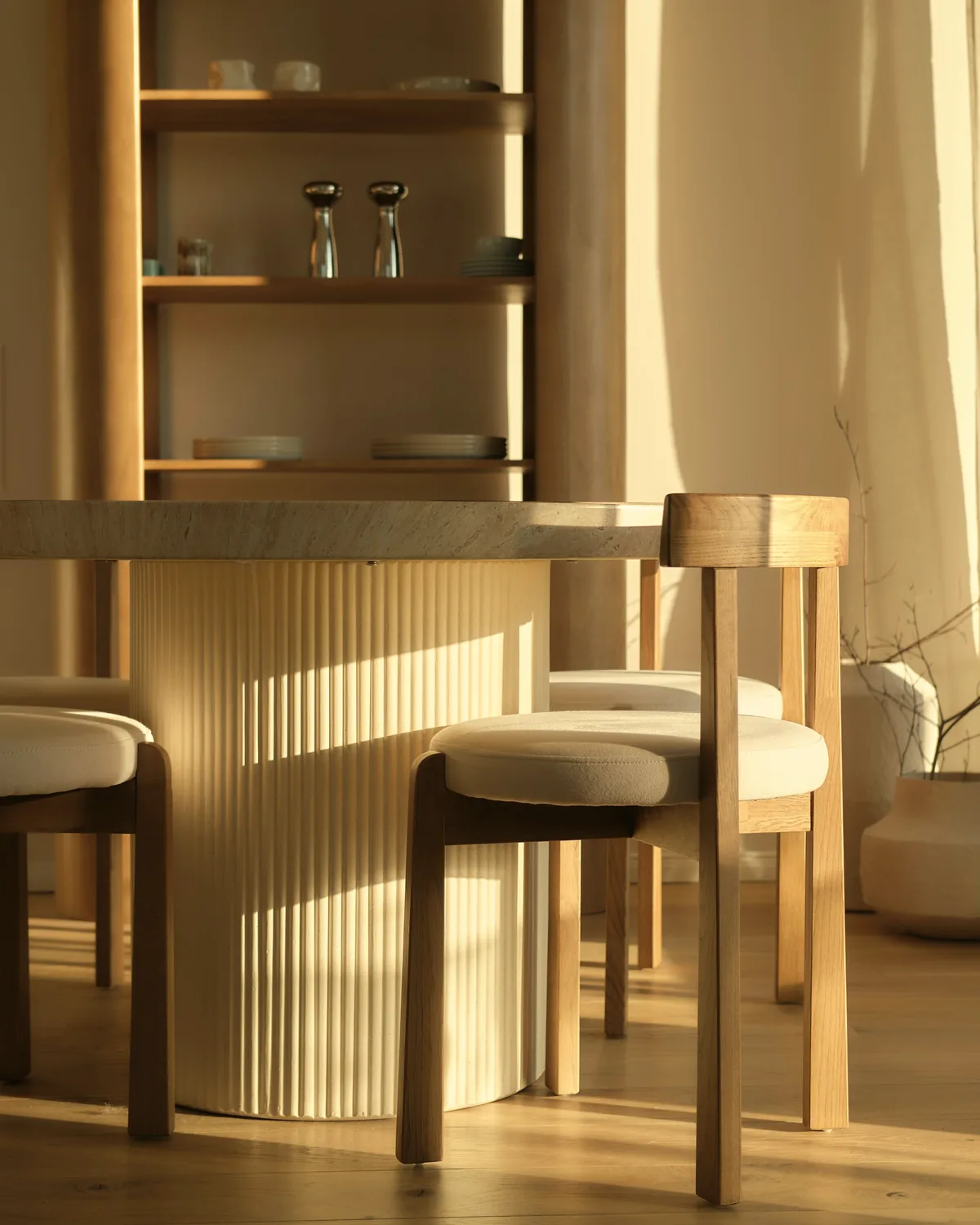 Oak dining chairs and a fluted pedestal table in low golden sunlight