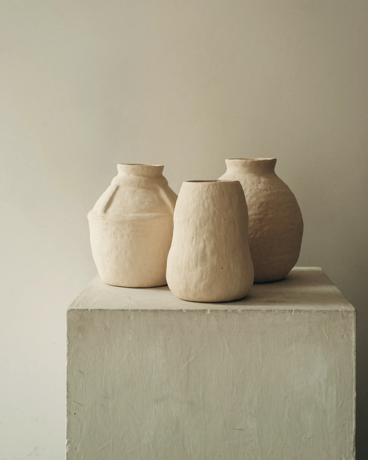 Three hand-built clay vessels on a plaster plinth