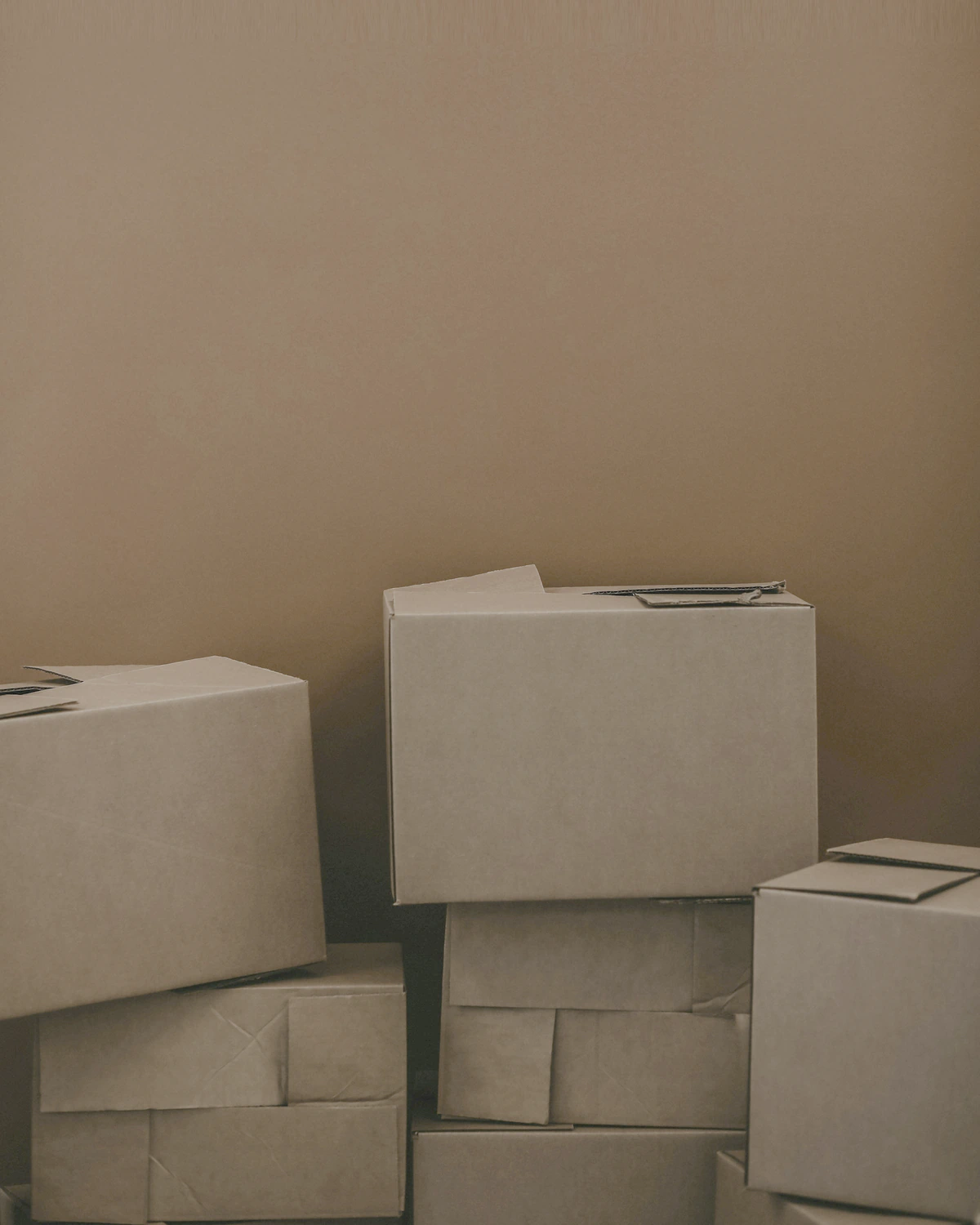 Stacked moving boxes against a warm wall