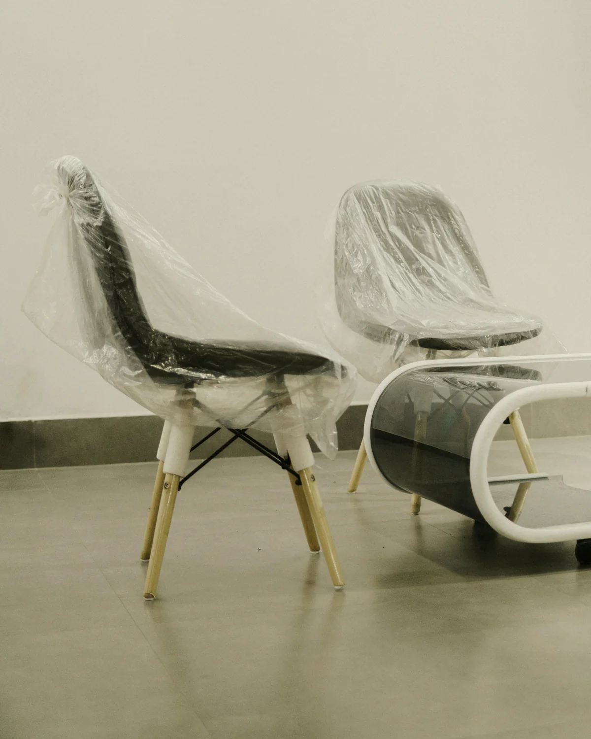 Two wrapped chairs placed in a bright, empty room