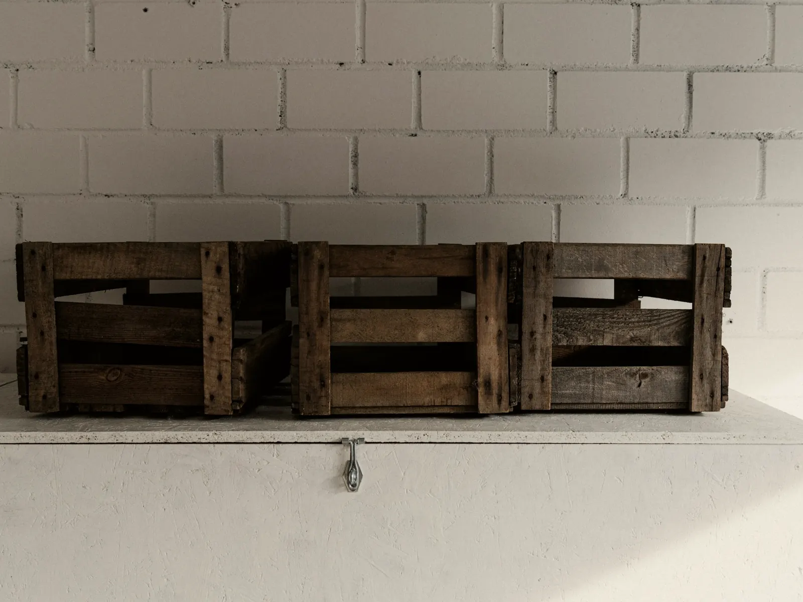 Three weathered wooden crates on a white chest against a painted brick wall