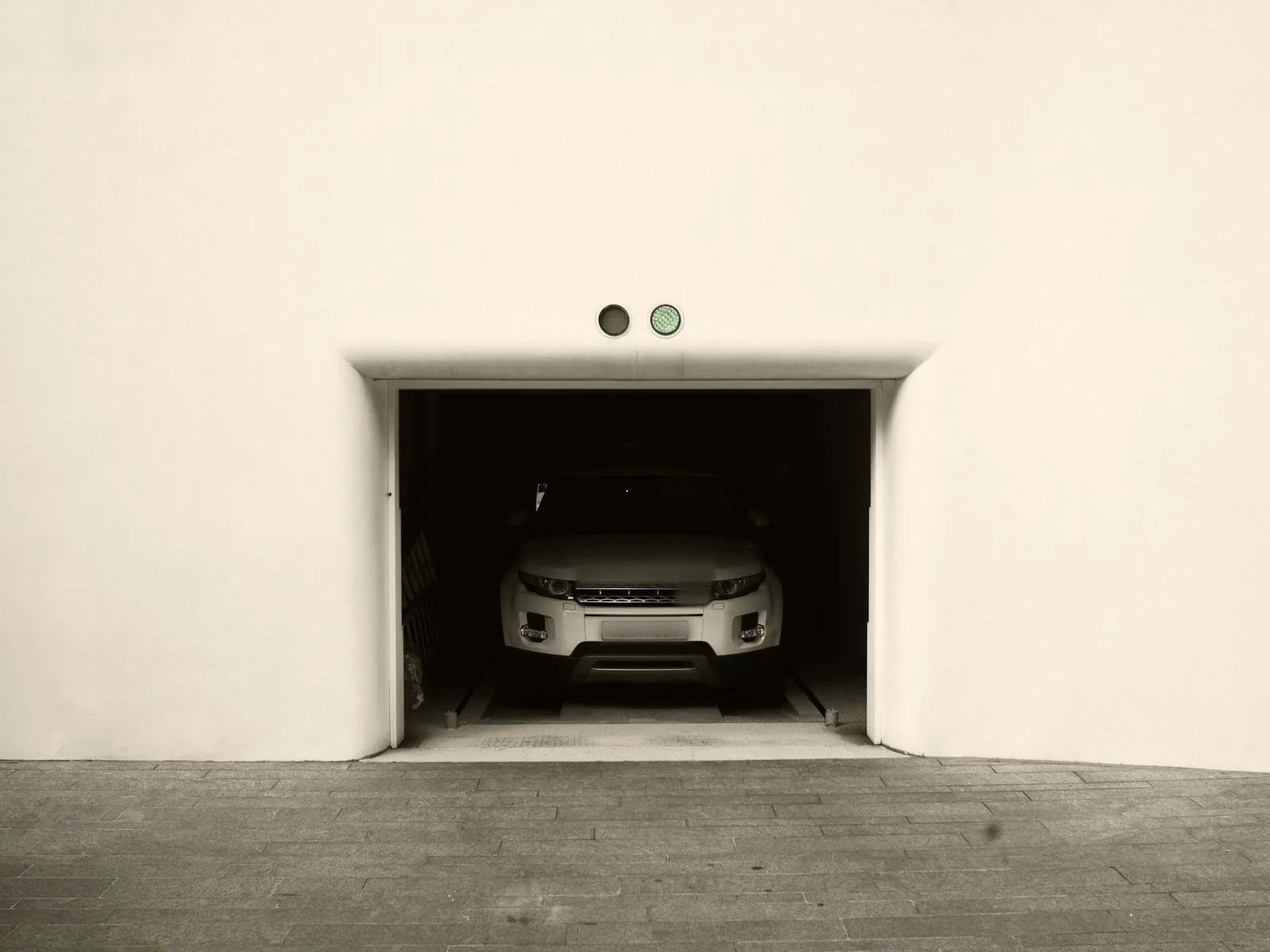 White SUV waiting inside a garage opening cut into a plain white wall